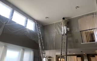 professional painter is painting the ceiling trim of a great room