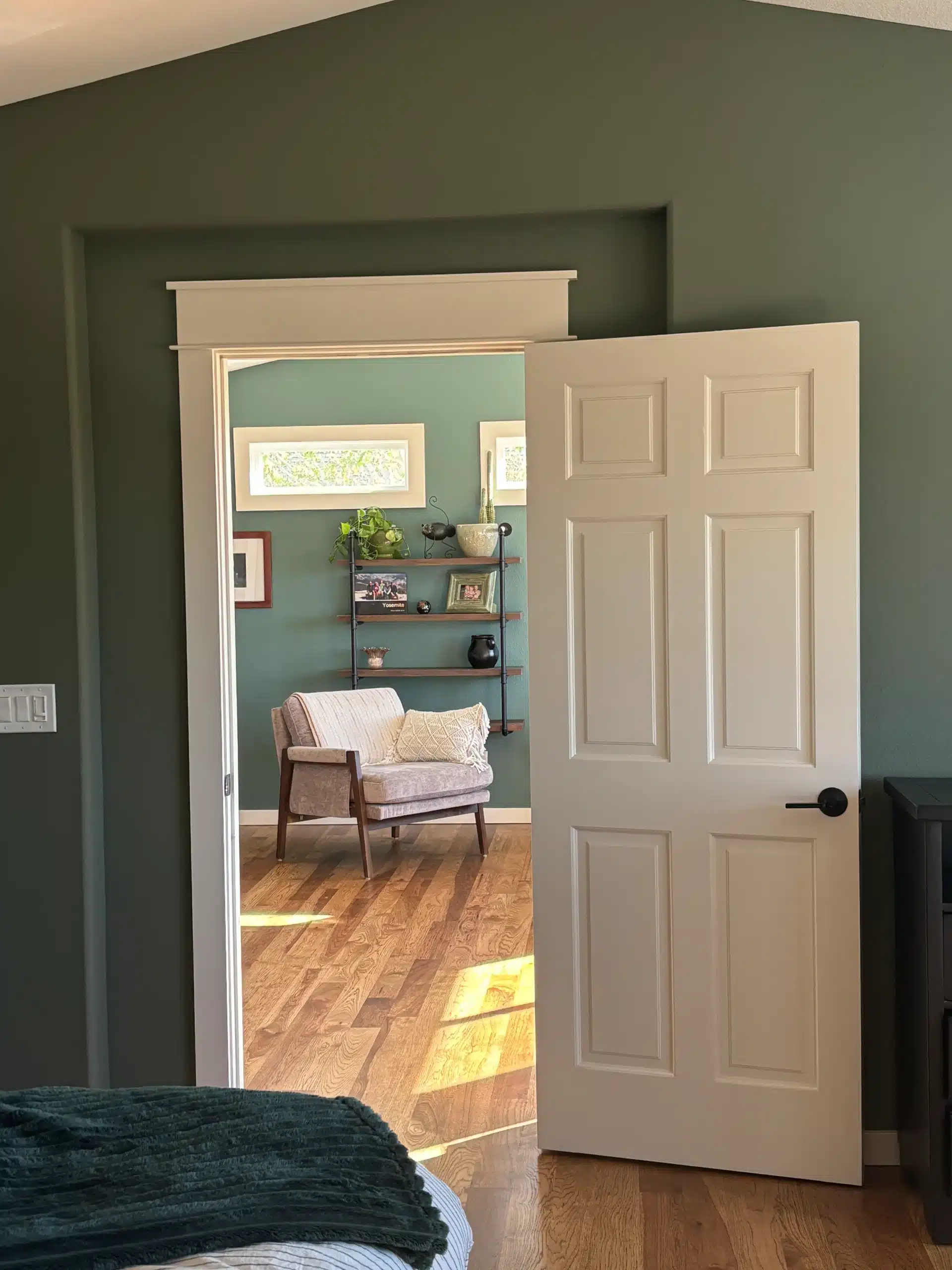 Seamless Interior Painting Transition Between Rooms with Green Walls View from a bedroom into another room, showcasing consistent dark green interior paint and crisp white trim.