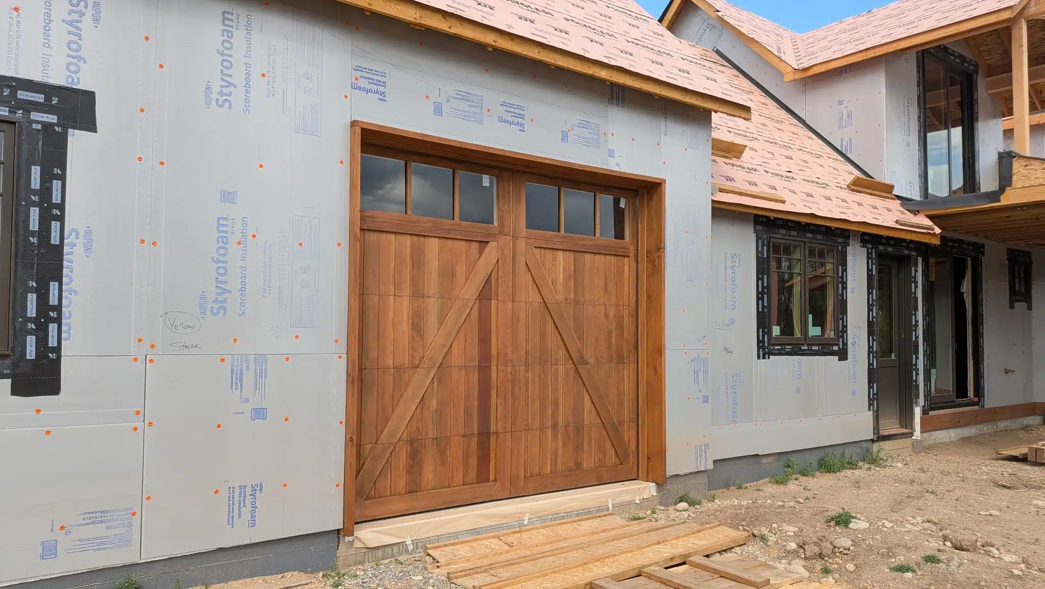 Expert Wood Staining for Custom Garage Doors A single custom wooden garage door on a new home, expertly stained to protect and beautify the wood.