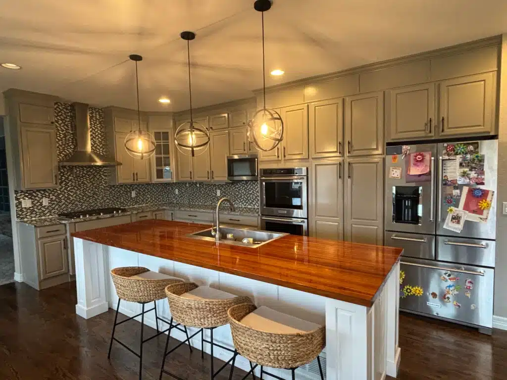 An elegant kitchen with freshly painted gray cabinets and a beautifully stained wooden island countertop.